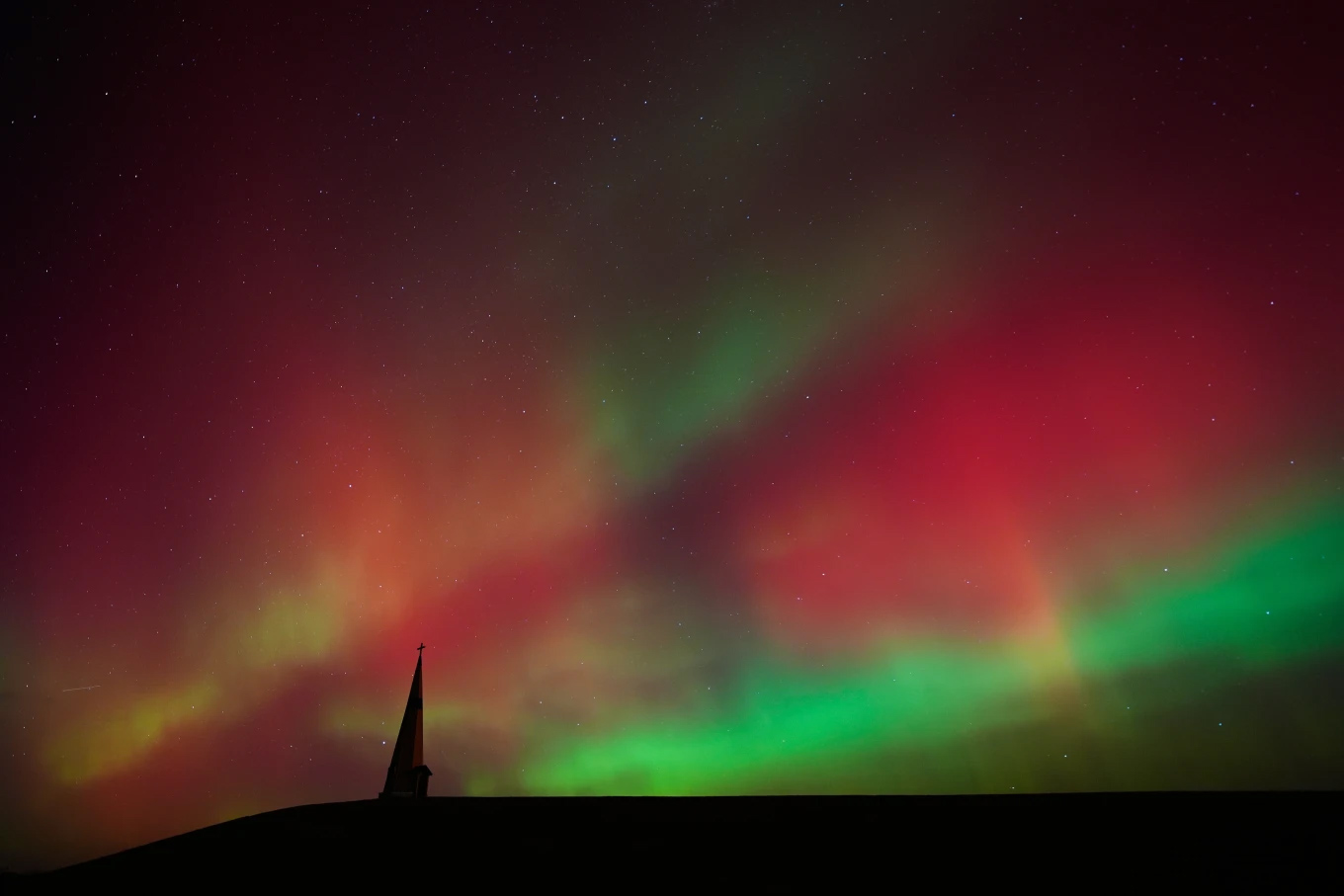 The northern lights fill the sky behind the Saint Joseph the Woodworker Shrine Tuesday, Nov. 11, 2025, near Valley Falls, Kan. (AP Photo/Charlie Riedel)
