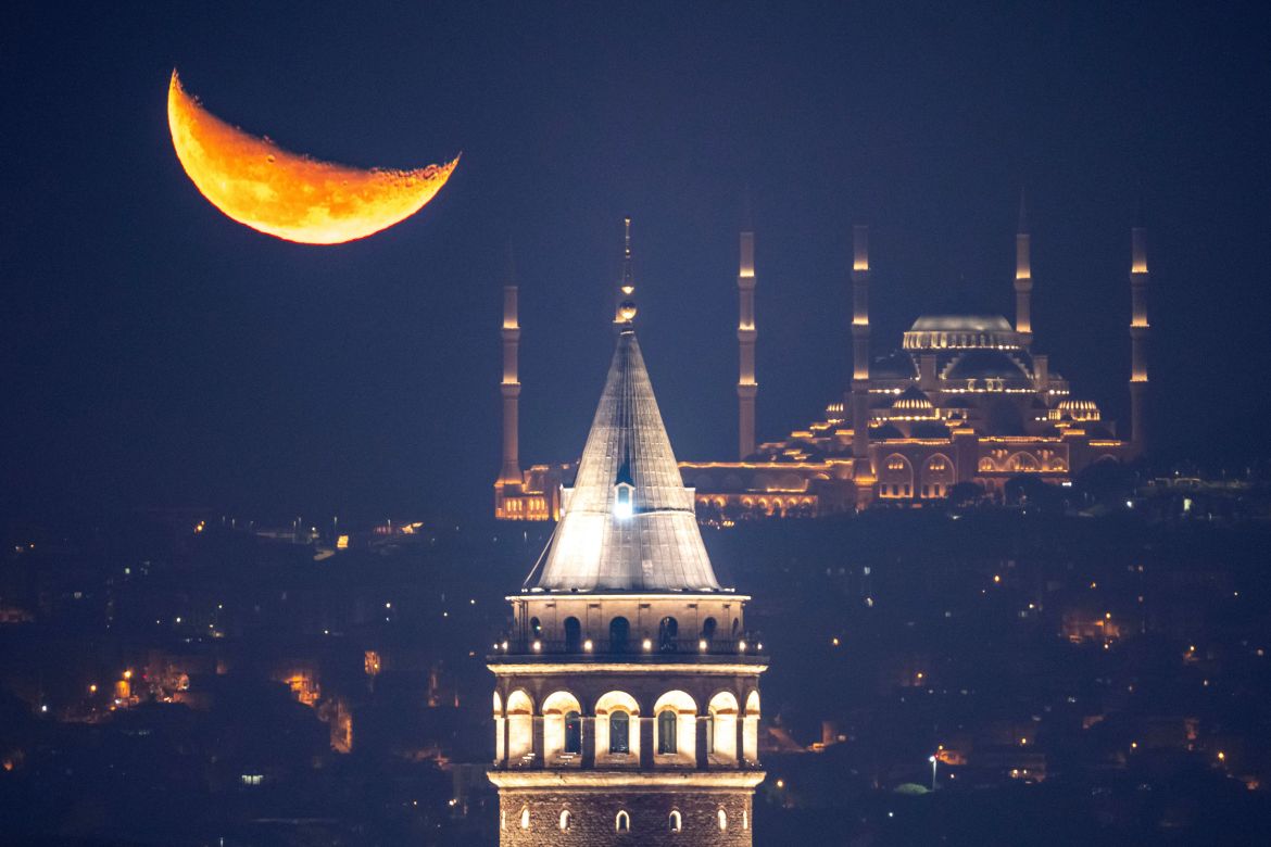 The crescent moon rises behind the Camlica mosque and Galata tower, in Istanbul, Turkey, early Friday, Nov. 14, 2025. (AP Photo/Emrah Gurel)
