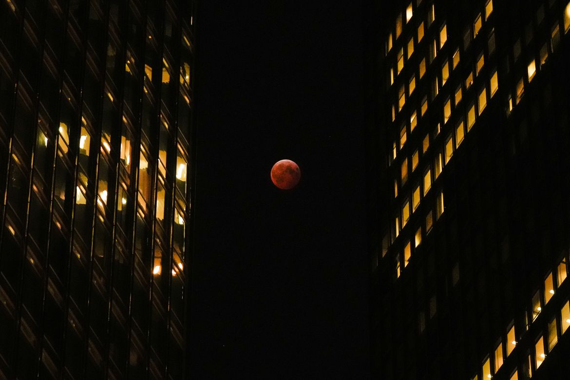 A total lunar eclipse, known as the blood moon, is visible between skyscrapers Friday, March 14, 2025, in downtown Chicago. (AP Photo/Kiichiro Sato)